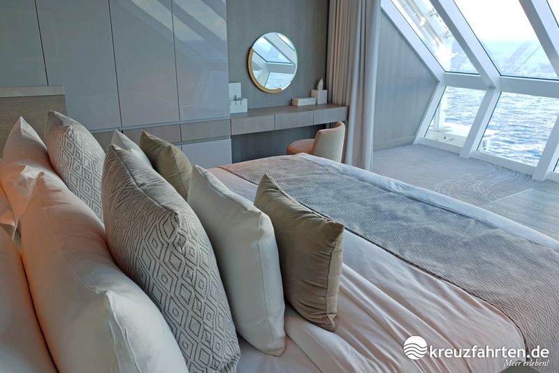 Vom gemütlichen Bett in der Iconic Suite an Bord der Celebrity Edge genießt man einen traumhaften Meerblick.