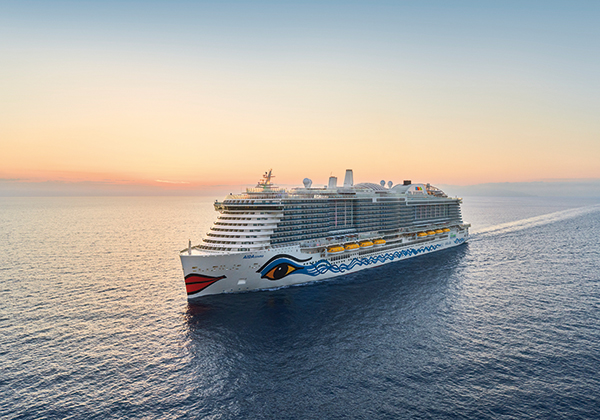 Ein AIDA-Schiff fährt über das Wasser bei Sonnenuntergang title=Foto beinhaltet die Vogelperspektive