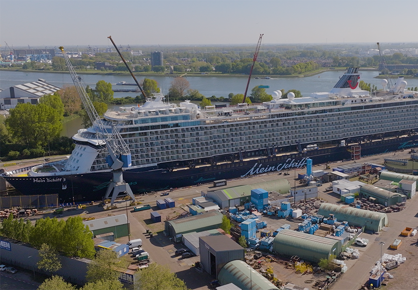 Mein Schiff 3 in Werft mit Kränen und Contaiergebäuden davor