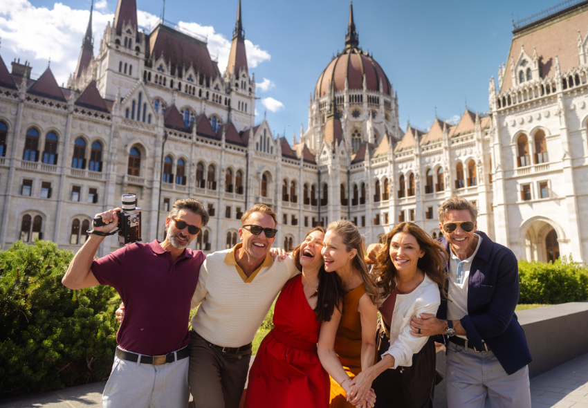 Before & After Stays Freundesgruppe lachend mit Kamera vor dem Parlamentsgebäude in Budapest