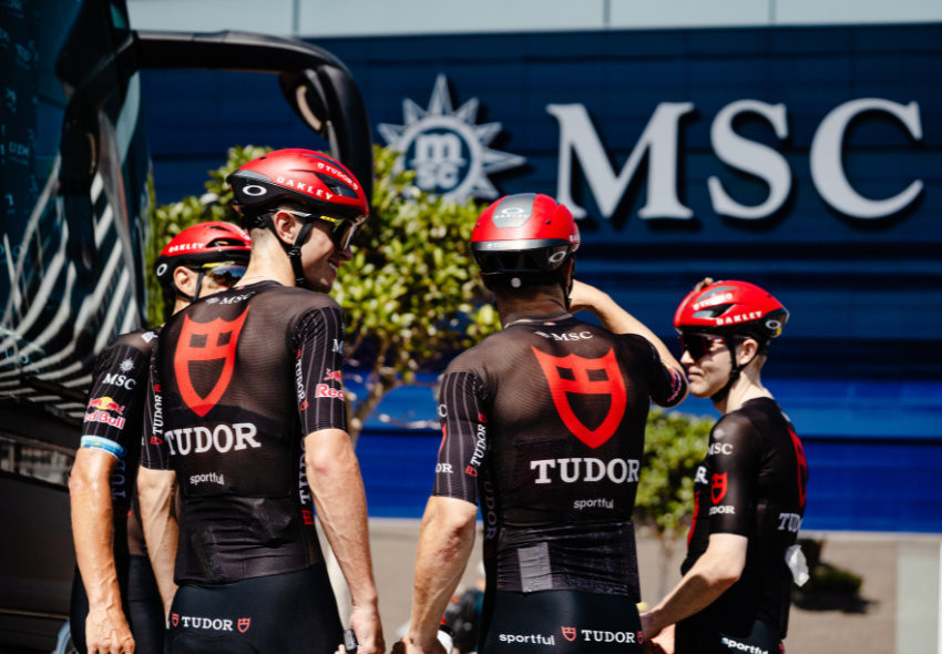 Tudor Pro Cycling Team mit MSC Cruises 4 Radfahrer stehen vor dem Bauch der MSC World Europa
