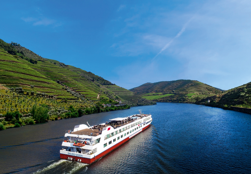 Das Flussschiff fährt zwischen grünen Weinbergtälern auf dem blauen Fluss