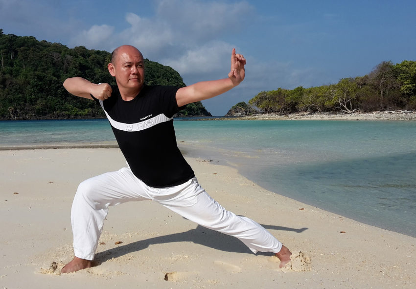 Awai Cheung Awai Cheung macht eine Tai-Chi Figur an einem Strand