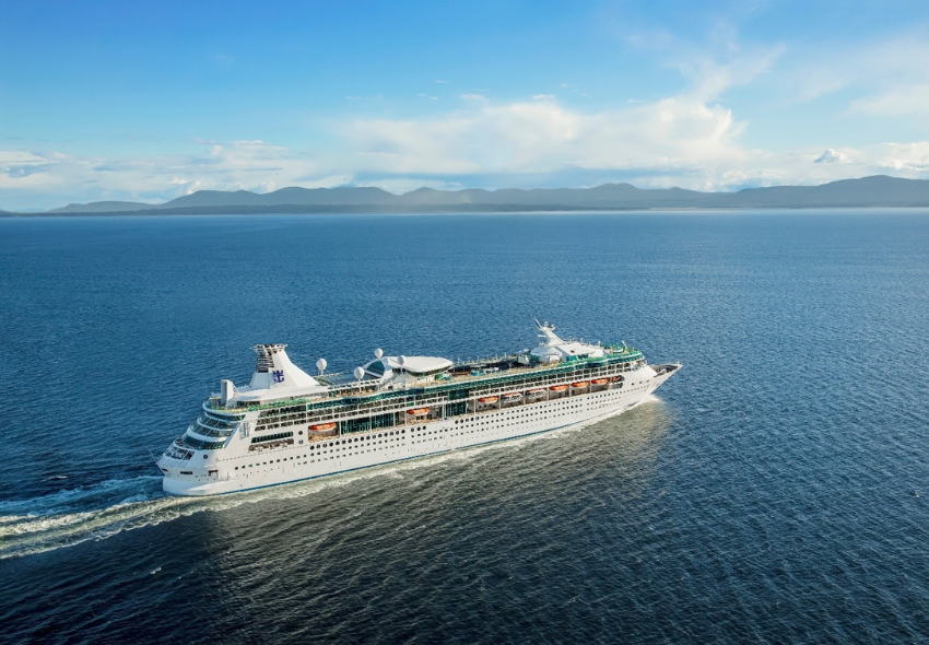 Die Rhapsody of the Seas von der Seite auf dem Meer mit Bergen im Hintergrund