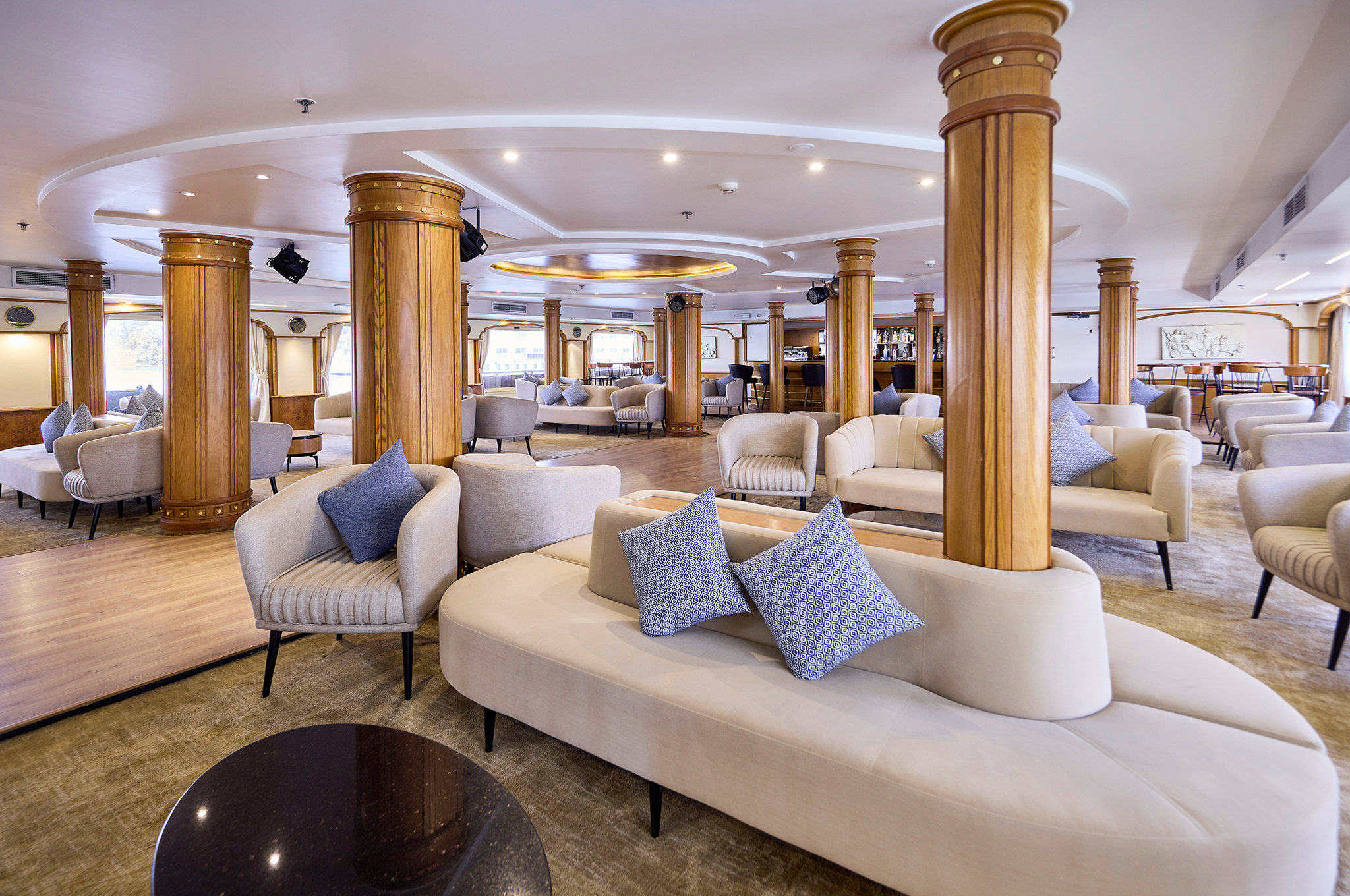 Helle und großzügige Lounge der MS Monte Carlo mit gemütlichen Sitzbereichen, Bar und Panoramafenstern