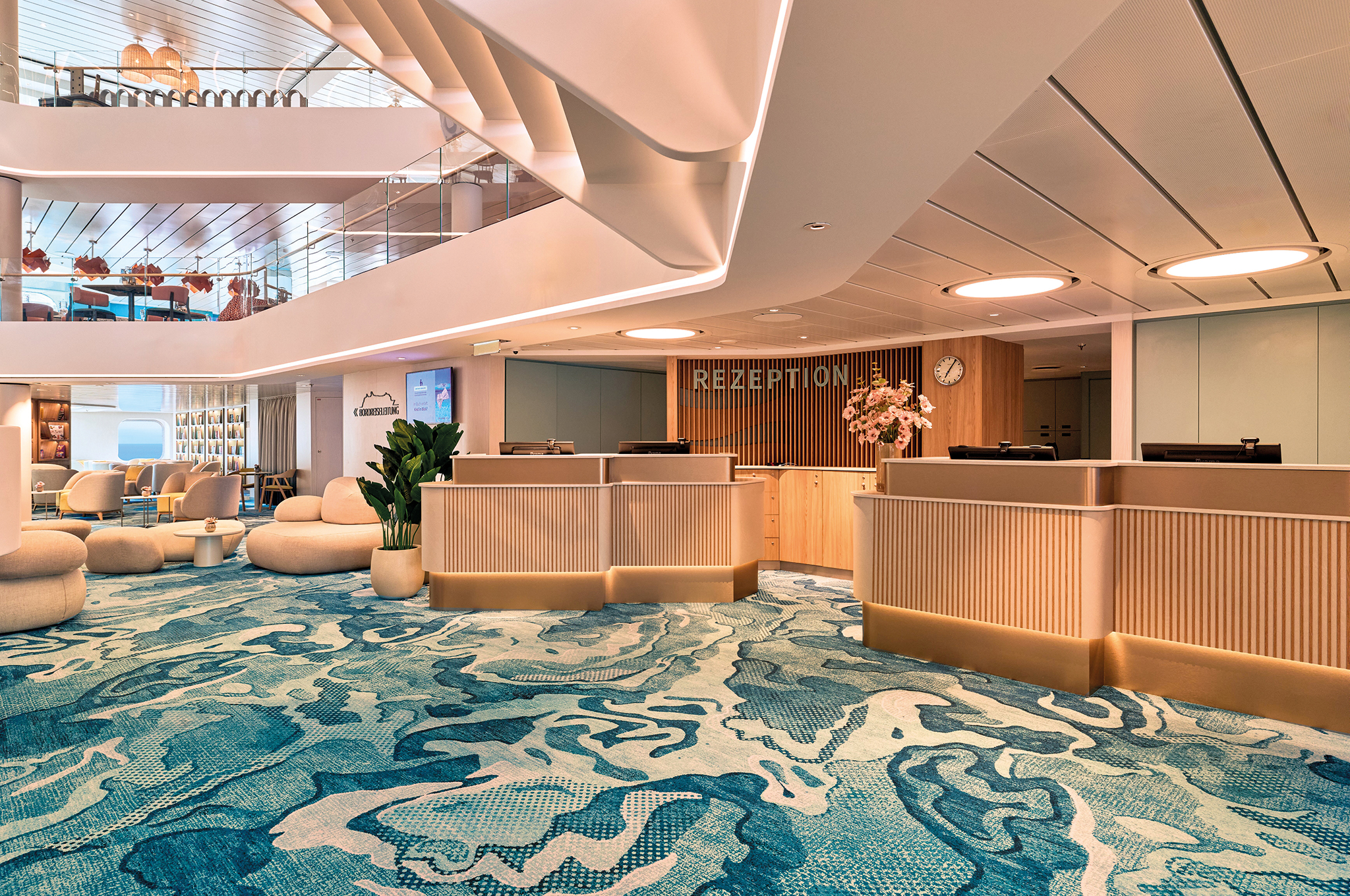Rezeption im Atrium der Mein Schiff Flow mit Sitzgruppen und Souvenirshop im Hintergrund