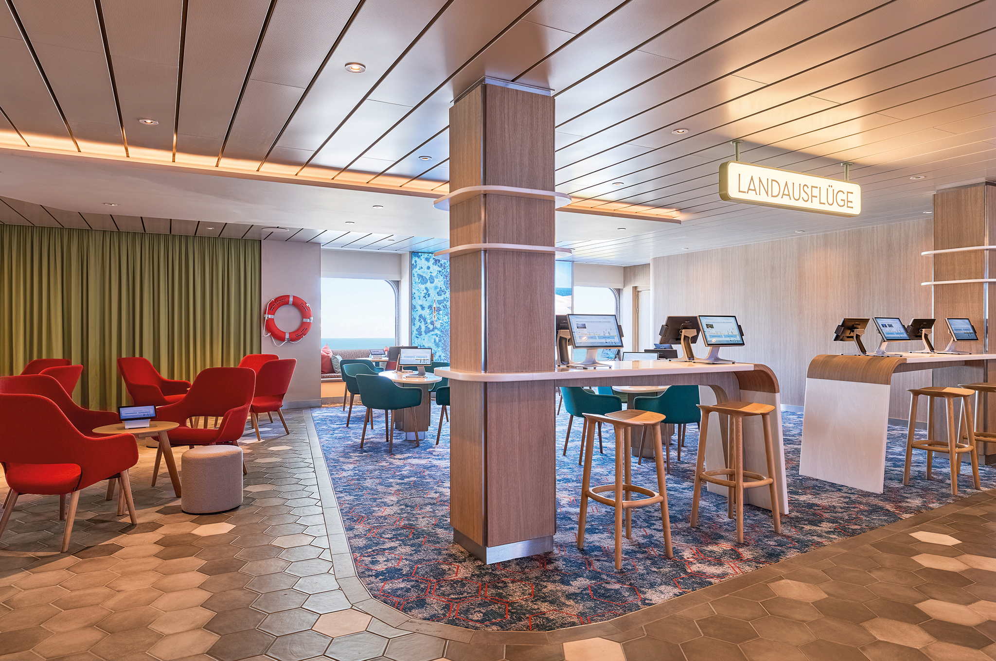 Landausflugsbüro an Bord der Mein Schiff Flow mit Sitzbereichen und Computern