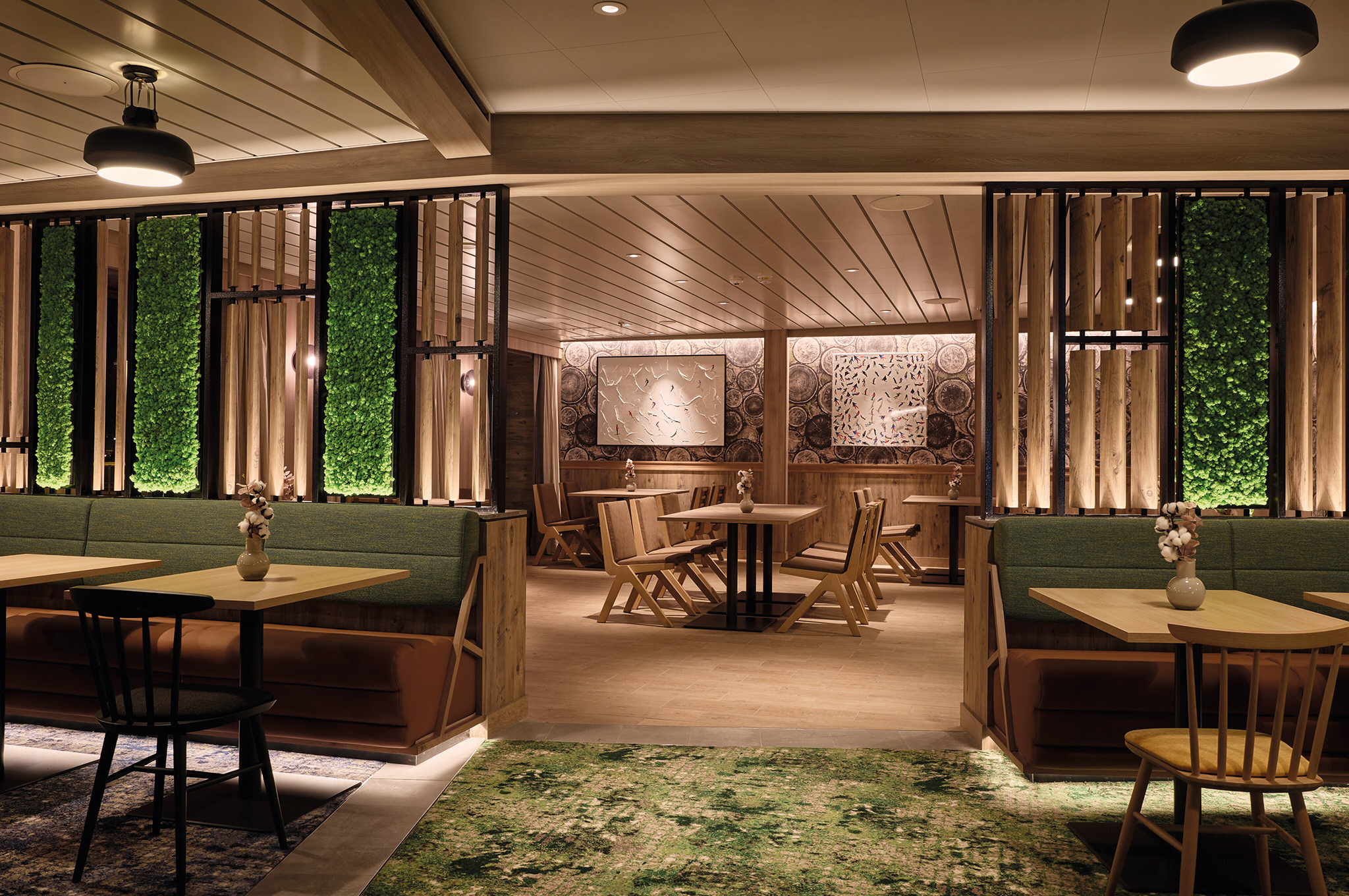 Innenansicht des Høfde Restaurants an Bord der Mein Schiff Flow mit Holzmöbeln und vertikalen Pflanzenwänden.